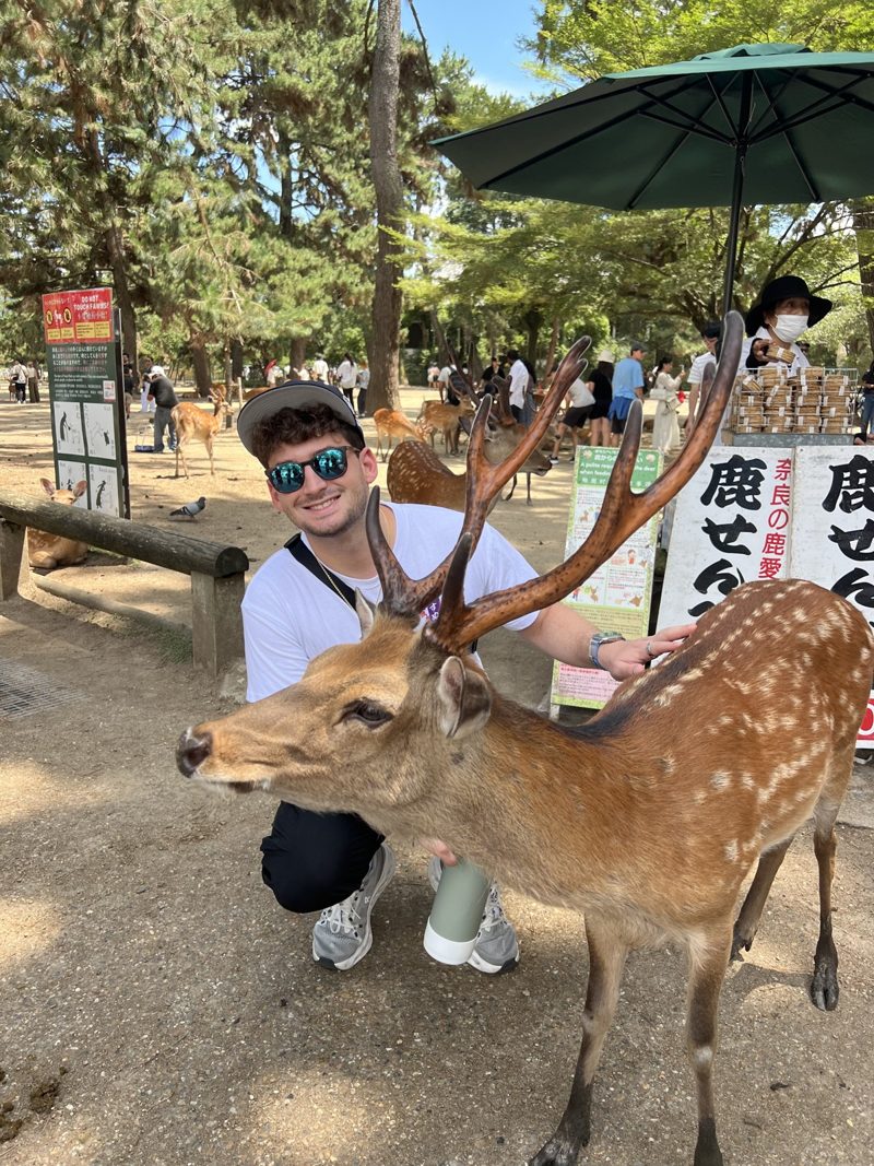 Tryfon smiling beside a deer outdoors
