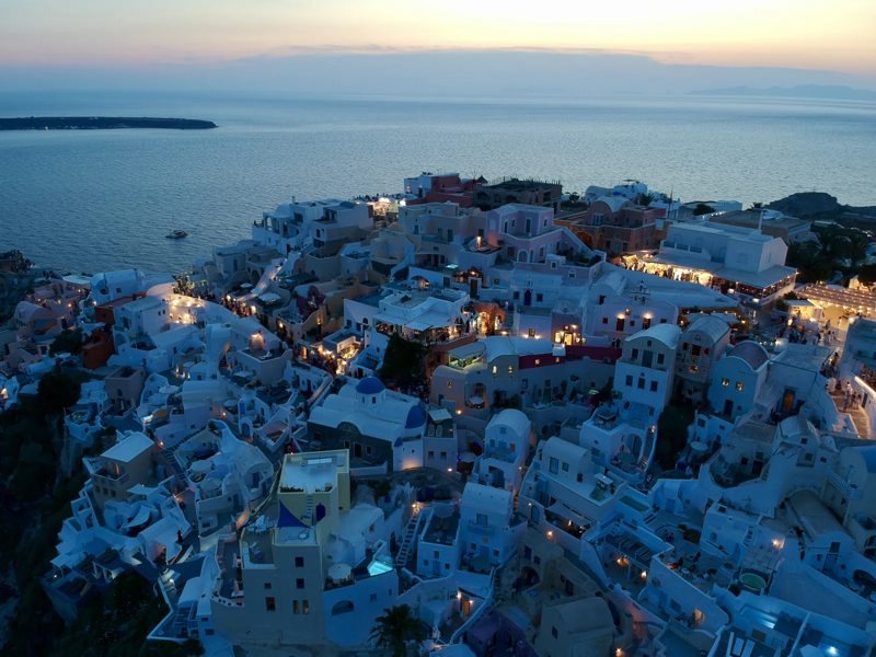 White buildings and blue domes overlooking the sea at dusk