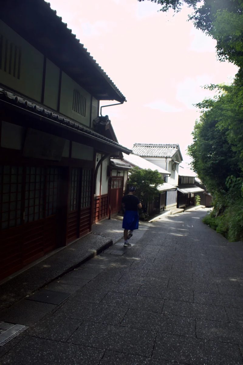 A person walking down a narrow street lined with traditional Japanese buildings