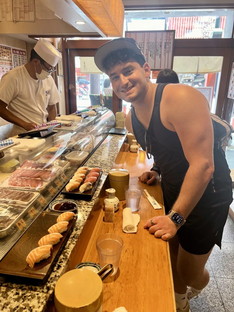 Tryfon seated at a sushi counter in Tokyo