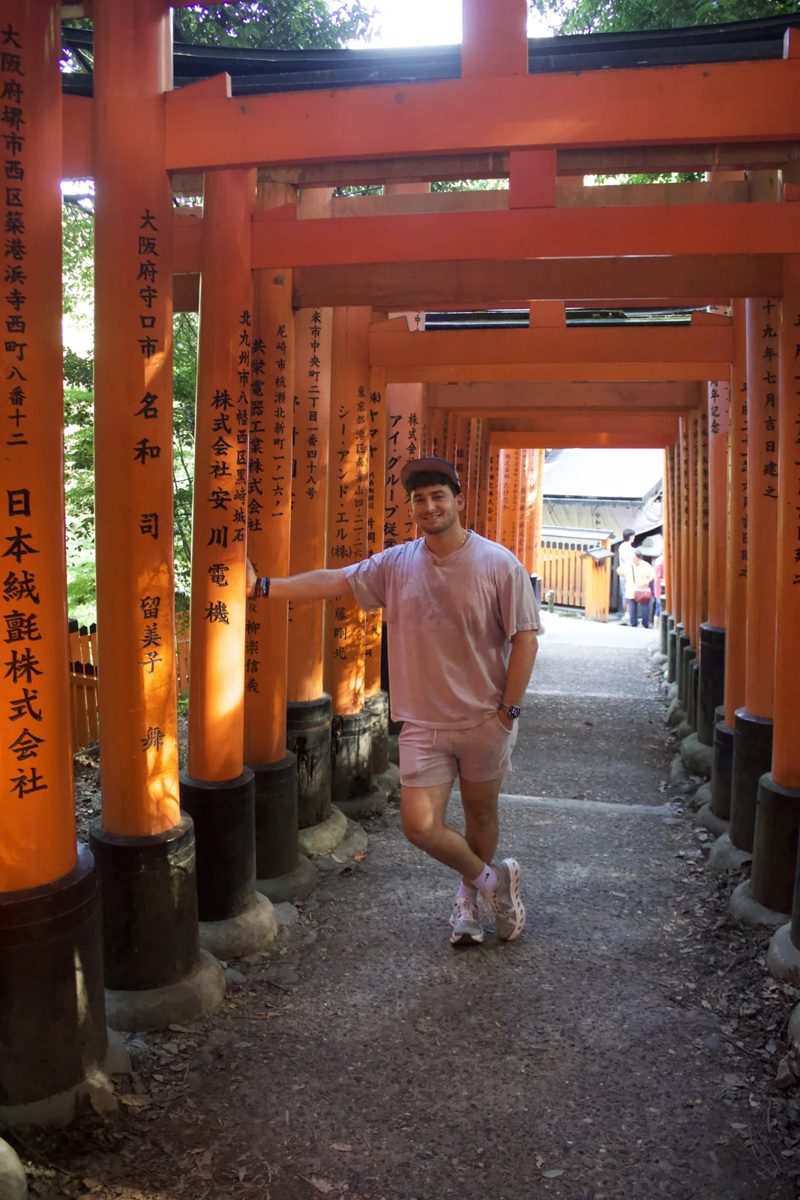 Tryfon standing beneath a passage of orange torii gates